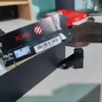 Xpg nvme m. 2 ssd resting on a pcie adapter on a workbench with red packaging in the background