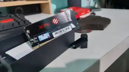 Xpg nvme m. 2 ssd resting on a pcie adapter on a workbench with red packaging in the background